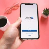 BANGKOK, THAILAND - May 17,2019: Top view of hand holding Apple iPhone XS with LinkedIn application on the screen. LinkedIn is a business-oriented social networking service.