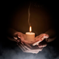 Hands holding candle over dark background. Christian Pray